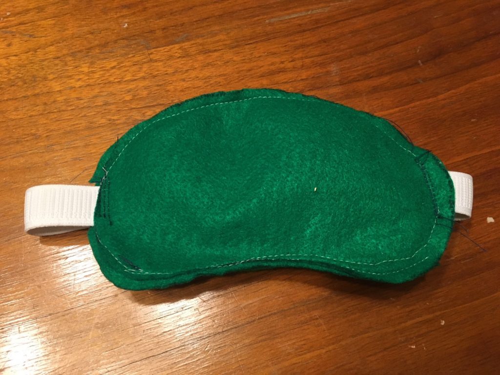 The front view of a green felt sleep mask.